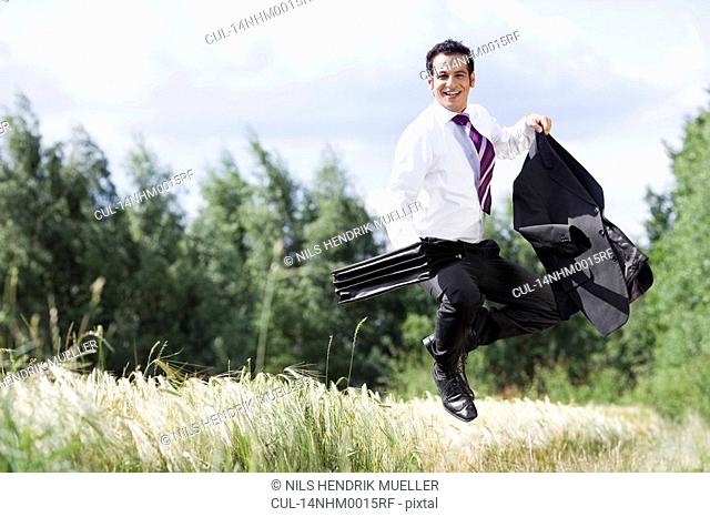 businessman jumping in cornfield