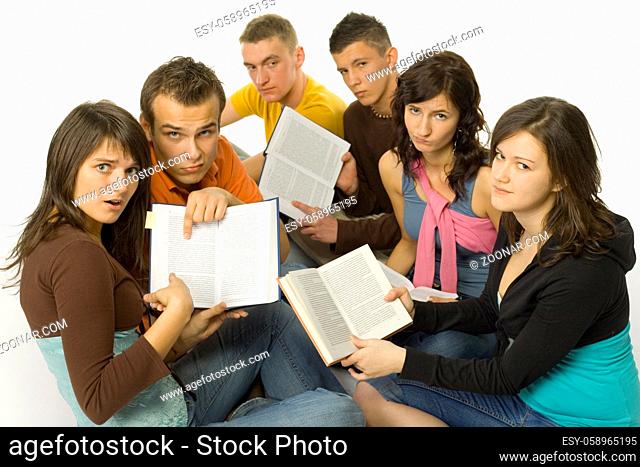 Group of students sitting and showing open books to the camera. They're looking sad