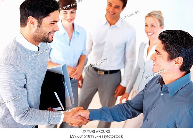 Happy business men shaking hands in front of team