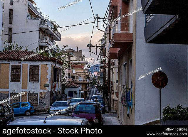 busy street in greece with cars and a snow-covered mountain in the back