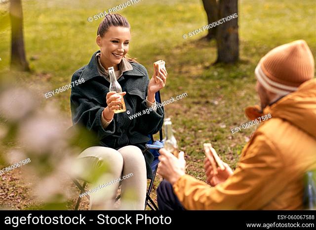 couple drinking beer with sandwiches at tent camp