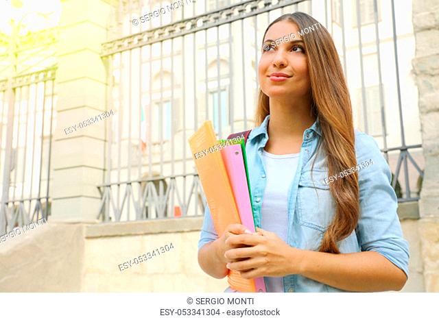 Student girl holding folders outdoor looking to the side the copy space