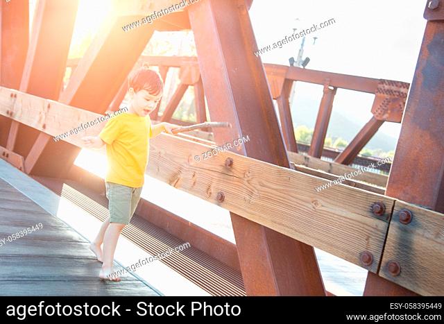 Mixed Race Chinese and Caucasian Boy Playing Alone on Bridge