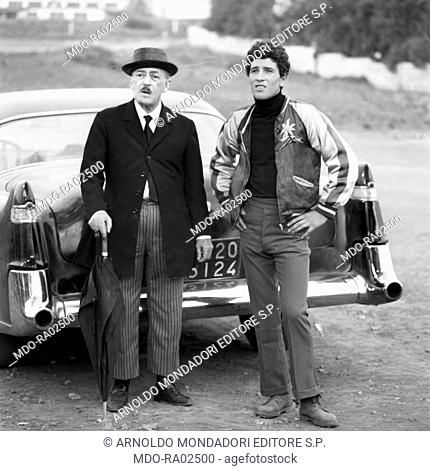 Italian artist TotÃ² (Antonio De Curtis) and Italian actor Ninetto Davoli (Giovanni Davoli) standing out of their car in the film The Hawks and the Sparrows