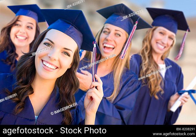 Happy graduating group of girls in cap and gown celebrating on campus