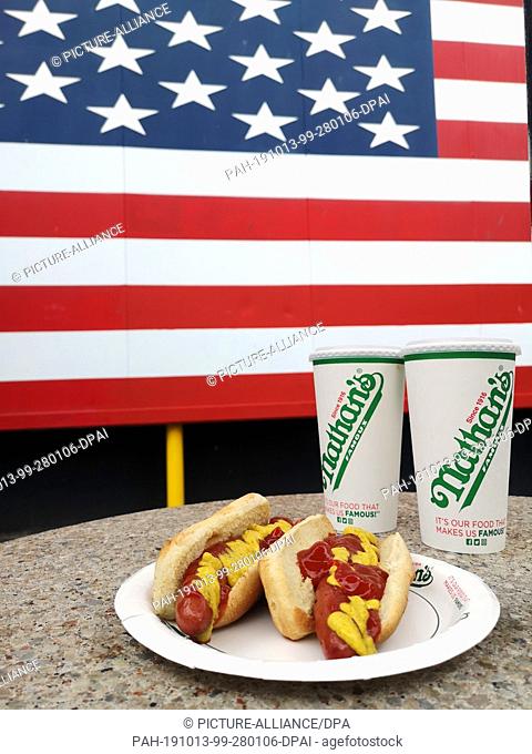 10 September 2019, US, New York: Hot Dogs on a printed paper plate and two paper cups from Nathan's Famous on Coney Island