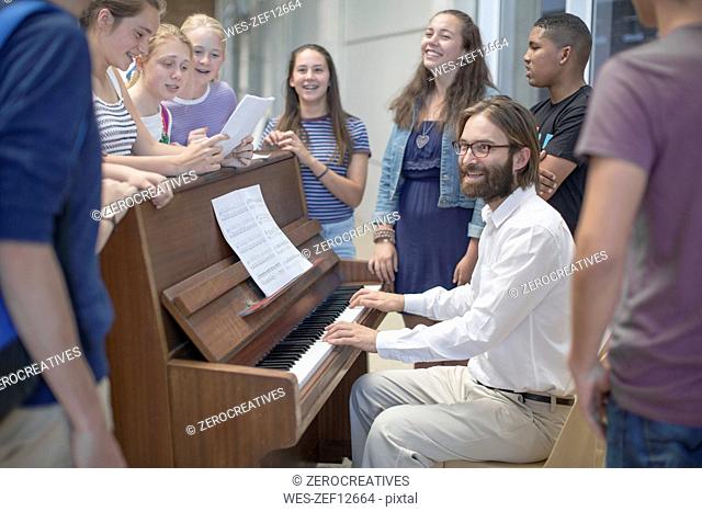 Teacher with group of students standing around piano
