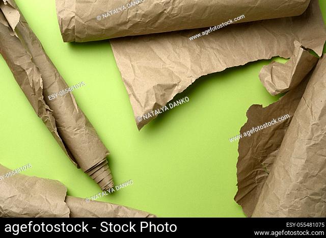 various roll of brown wrapping paper on green background, top view