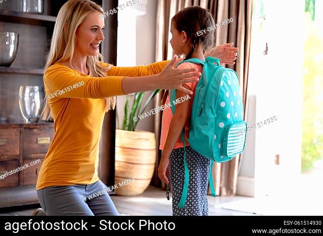 Caucasian woman helping her daughter preparing for leaving to school