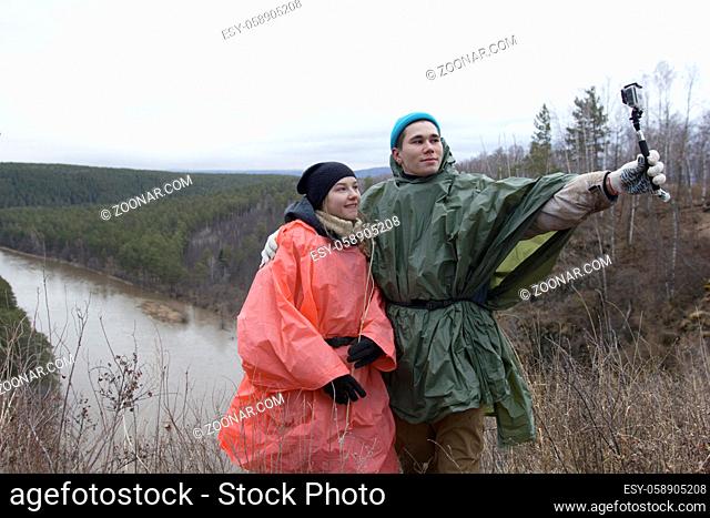 Young loving couple making selfie in the hillside to the river, telephoto shot