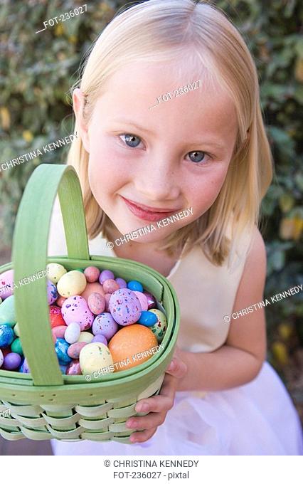 Young girl holding basket full of Easter eggs