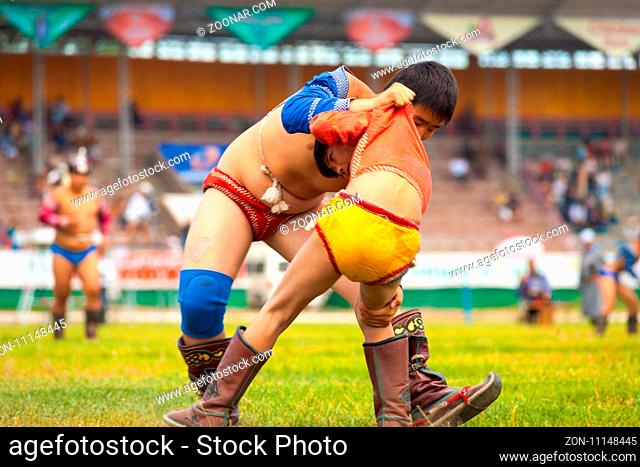 Ulaanbaatar, Mongolia - June 11, 2007: Closeup of two boys locked in wrestling match on field inside the National Sports Stadium at the Naadam Festival