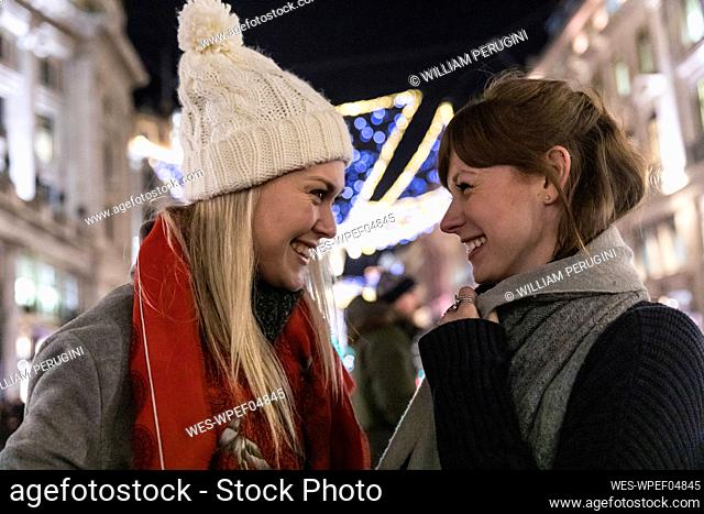 Happy female friends wearing warm clothing looking at each other