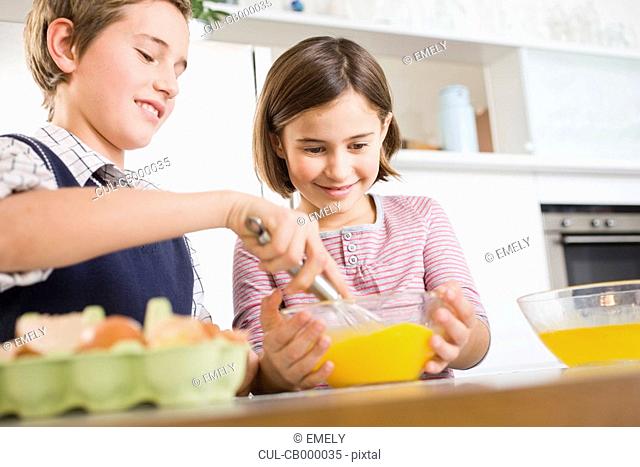 Boy and girl stirring egg yolk together