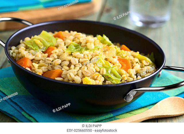 Vegan stew made of wheat grains, savoy cabbage, carrot, pumpkin and onion, photographed with natural light (Selective Focus, Focus one third into the dish)