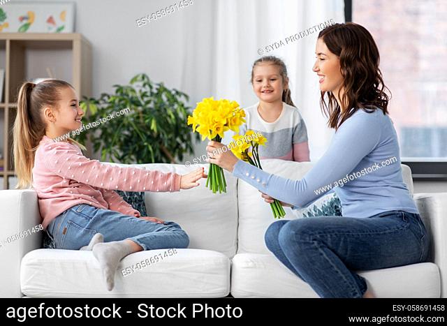 daughters giving daffodil flowers to happy mother