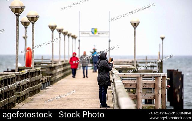 16 December 2023, Mecklenburg-Western Pomerania, Graal-Müritz: Strollers walk along the pier at the Baltic seaside resort