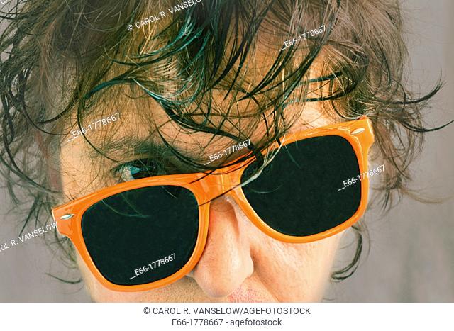 portrait of woman with wet hair and tilted orange sunglasses Processed with InstaGram look with soft grey background