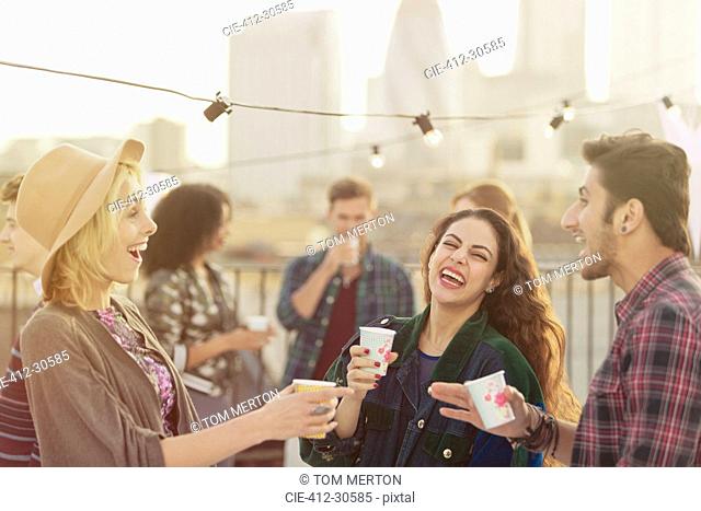 Young adult friends laughing and drinking at rooftop party