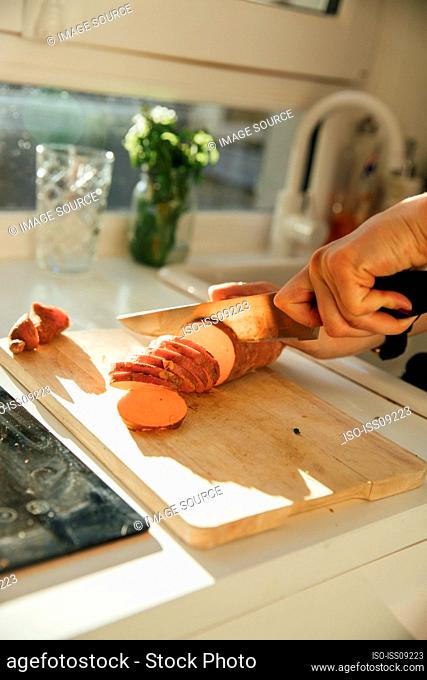 Hand of woman slicing sweet potato
