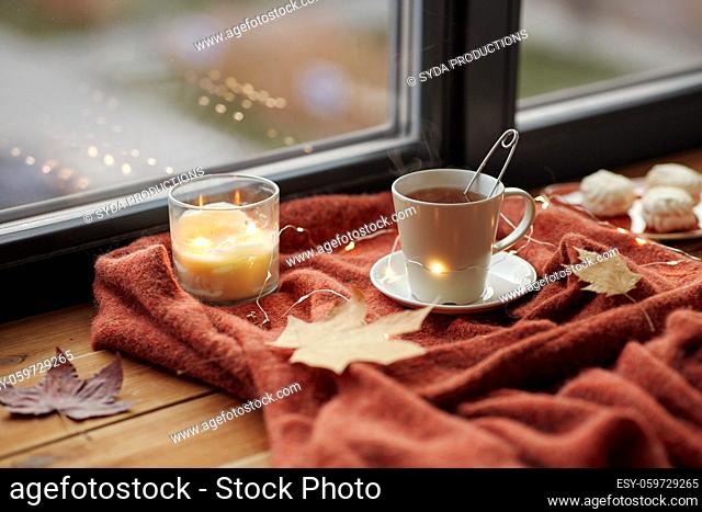 cup of tea and candle on window sill in autumn