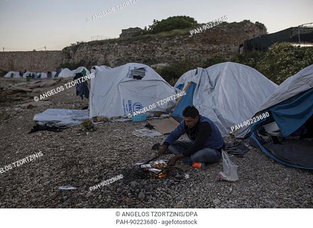 A refugee cooks on an open fire at their tent at the Souda refugee camp on the island of Chios, Greece, 26 April 2017. Some 3700 refugees and migrants are...