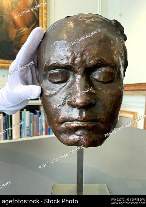 30 June 2022, Great Britain, London: A woman displays a bronze cast of a living mask of composer Ludwig van Beethoven on display during London Art Week