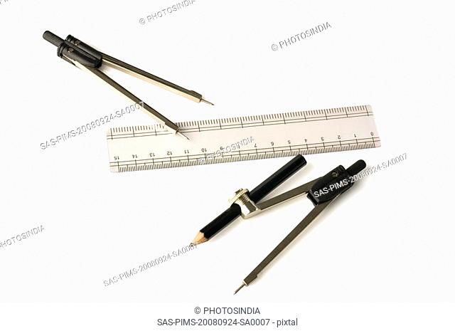 Close-up of drawing compasses with a ruler and a pencil