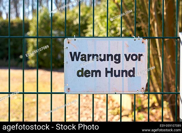Schild an einem Zaun mit der Aufschrift Warnung vor dem Hund