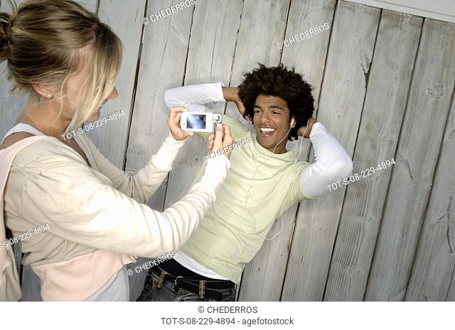 Close-up of a young woman taking a photograph of a young man