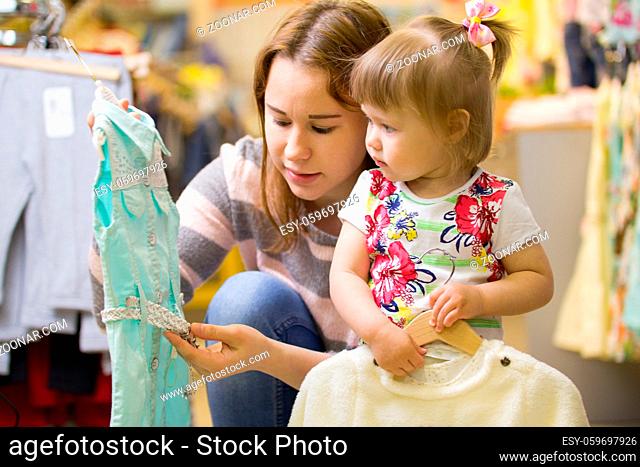 Attractive mother shows her daughter a beautiful dress, telephoto shot