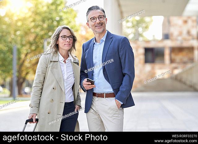 Thoughtful businesswoman and colleague standing on footpath