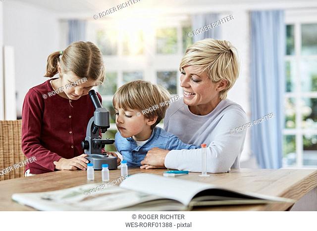 Mother with daughter and son using microscope at home