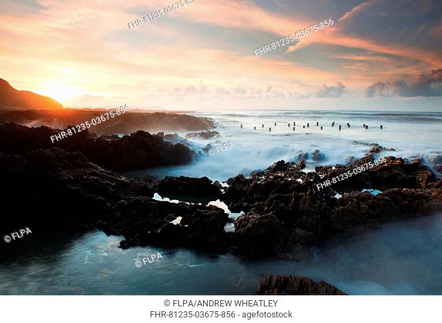 View of Victorian pier remains exposed during low tide at sunset, Westward Ho!, North Devon, England, november
