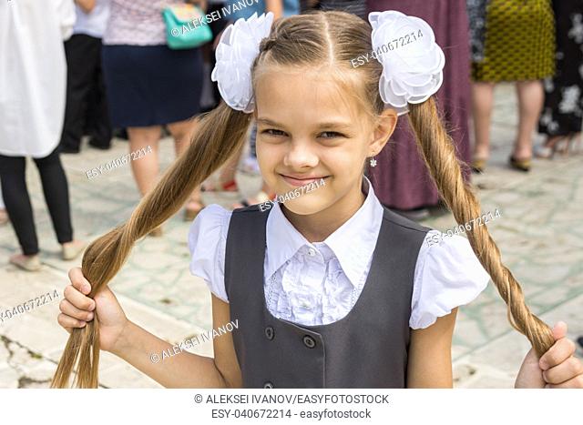 Schoolgirl at the festival on September 1 holds her long hair in her hands