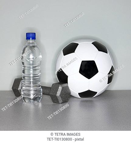 Soccer ball next to water bottle and dumbbell