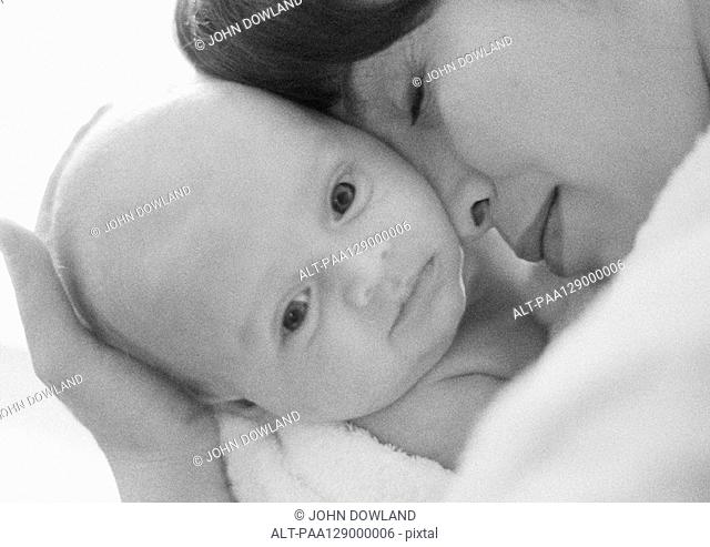 Mother holding infant against face, close-up, b&w