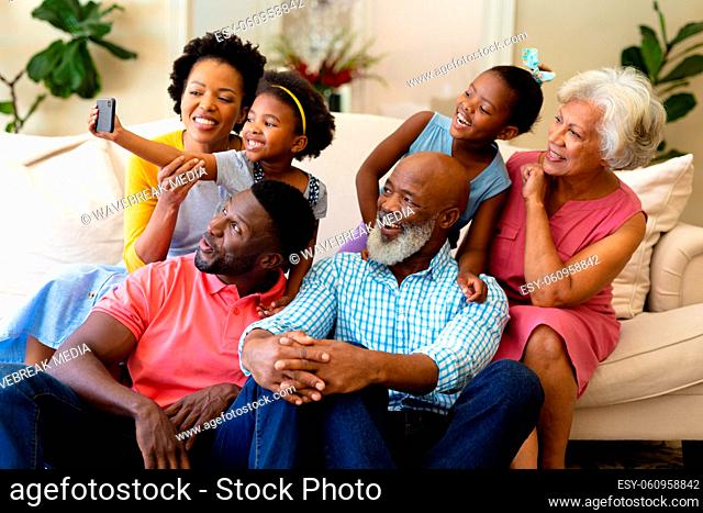 African american three generation family taking a selfie sitting together on the couch at home