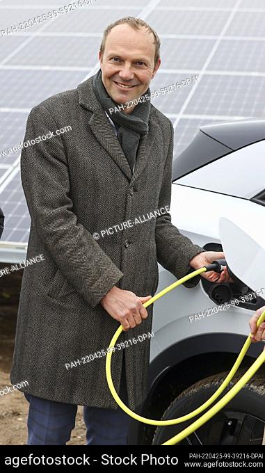 25 April 2022, Saxony, Zwickau: Wolfram Günther (The Greens), Saxony's energy and climate protection minister, plugs the charging plug into a VW ID