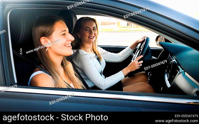 Portrait of female driver talking to smiling woman sitting on passenger seat while driving a car