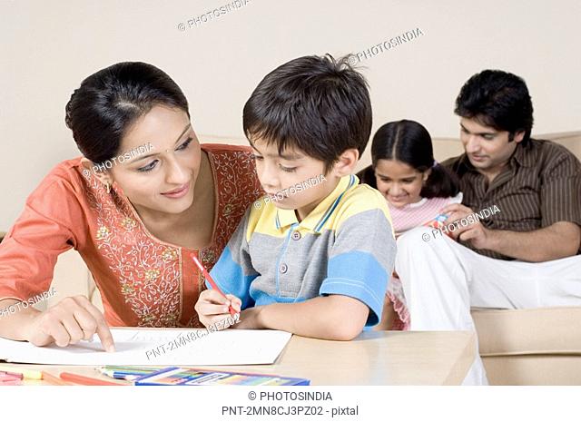 Boy drawing with his mother and a young man sitting with his daughter on a couch