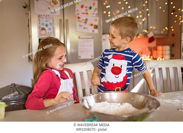 Siblings playing with flour in the kitchen
