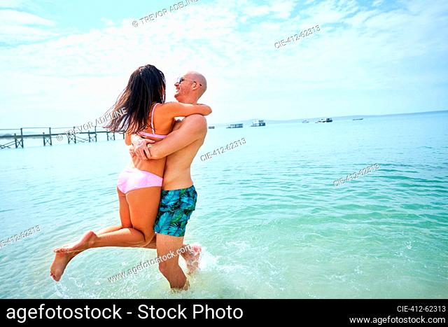 Happy, carefree couple playing in sunny summer ocean