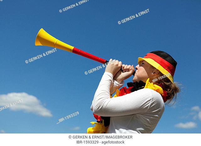 Young woman blowing in a Vuvuzela, black red gold, FIFA World Cup 2010