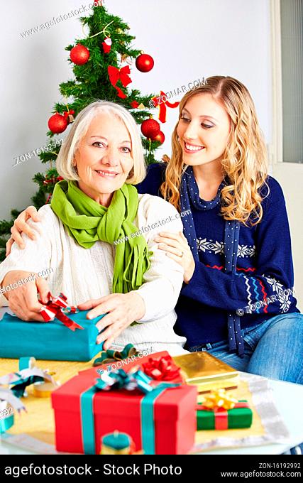 Seniorin und Tochter verpacken zusammen ein Geschenk an Weihnachten