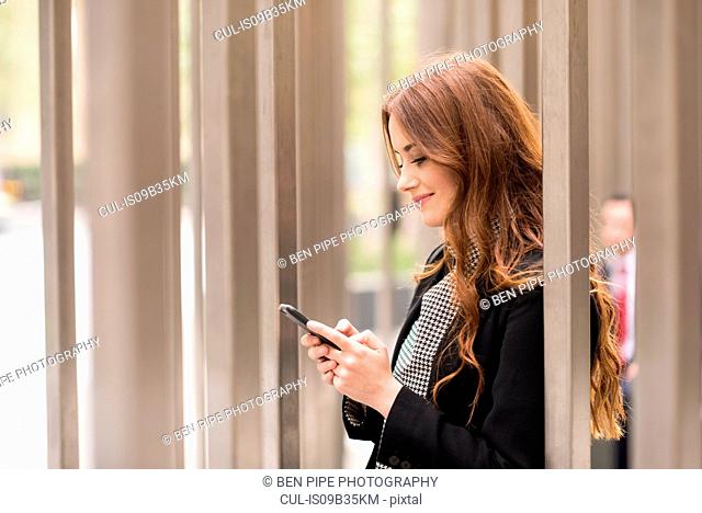 Businesswoman in city looking at smartphone