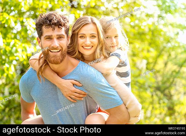 Strong and reliable man supporting his family by carrying wife and son piggyback