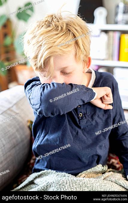 Boy coughing in arm
