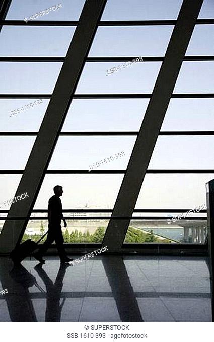 Man walking and pulling luggage in an airport, Shanghai Airport, China