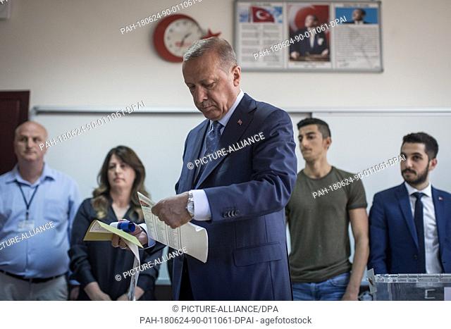 Turkish President Tayyip Recep Erdogan holds his ballot papers to vote in Turkey's elections at a polling station, in Istanbul, Turkey, 24 June 2018